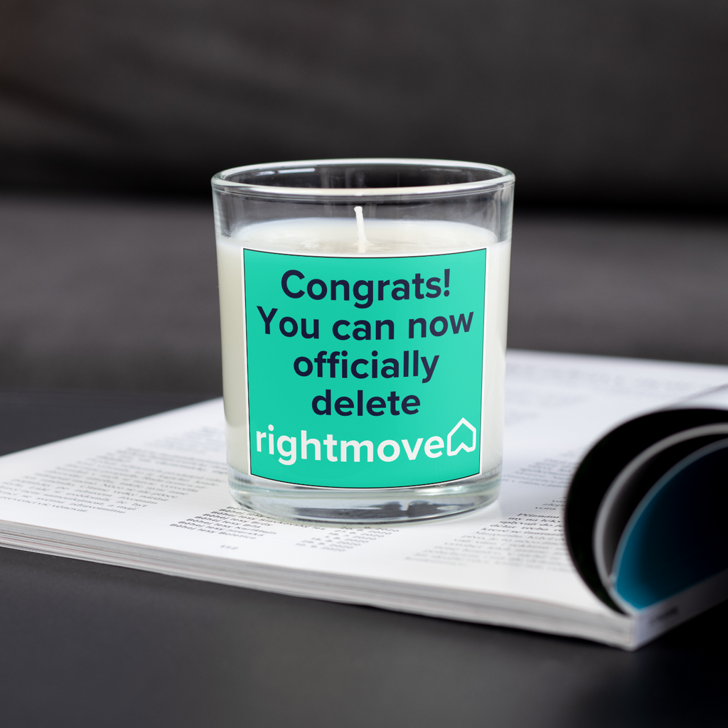Funny housewarming candle saying you can now officially delete Rightmove on an open magazine