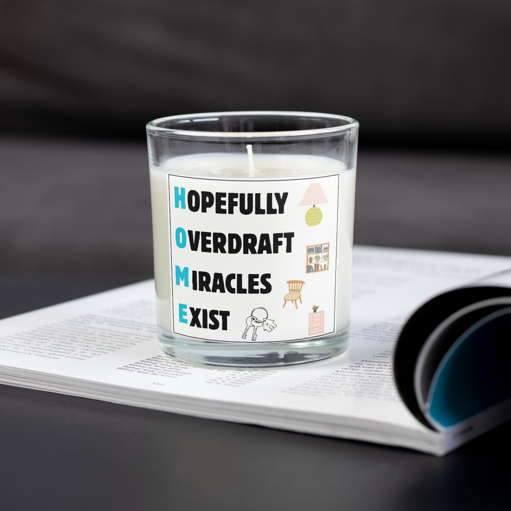 Hopefully Overdraft Miracles Exist housewarming candle on an open magazine